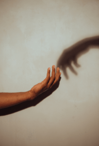 Hand reaching out to shadow on wall.