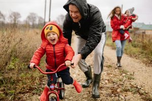 Child learning to ride bike with family's help.