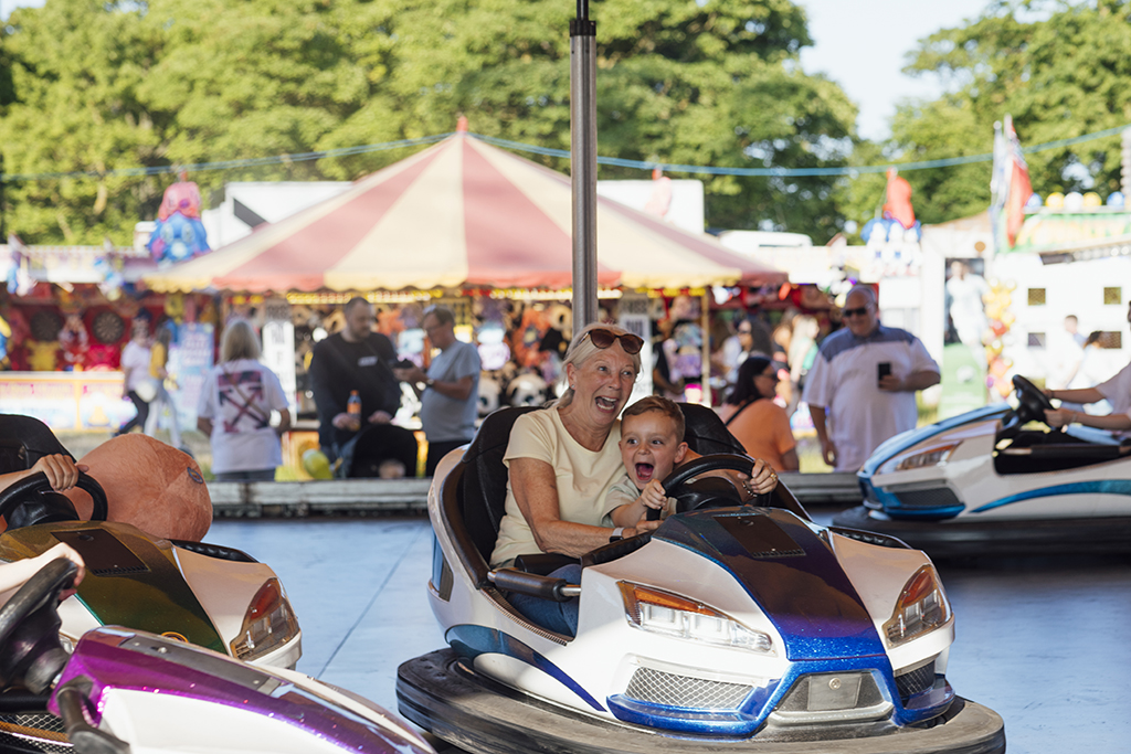 Grandmother and child enjoying bumper cars at a fair.