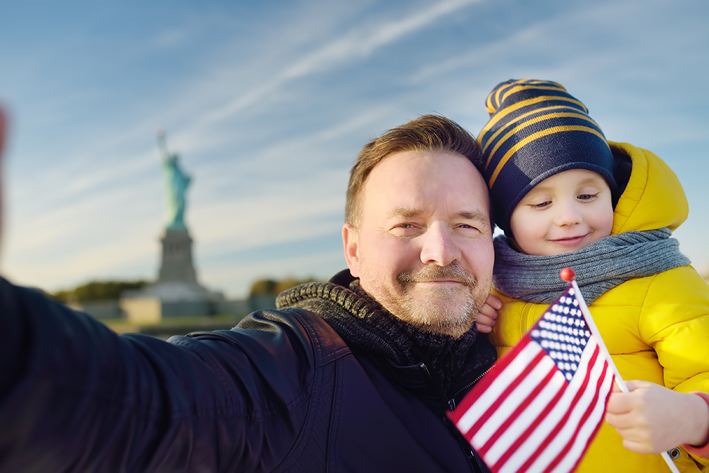 Father and son selfie with Statue of Liberty.