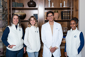 Four smiling healthcare professionals indoors.