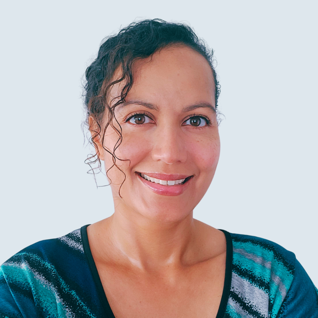 Woman smiling, teal top, white background.