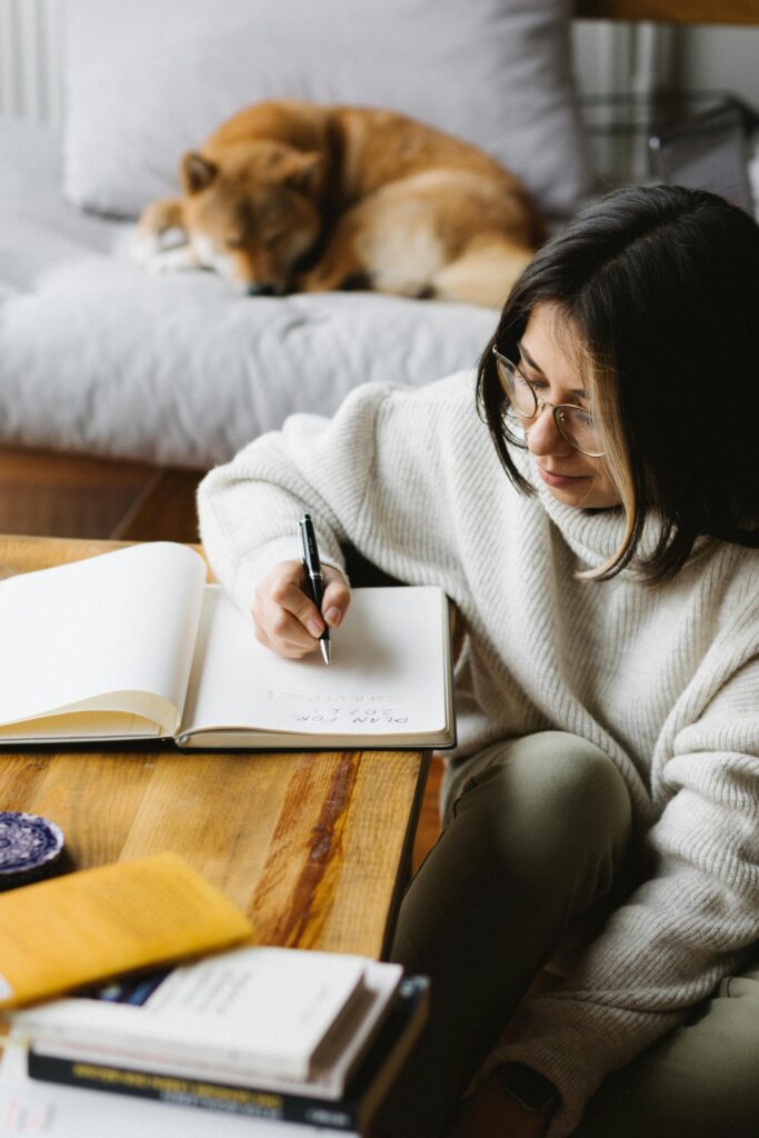 Person writing in notebook, dog sleeping on couch.