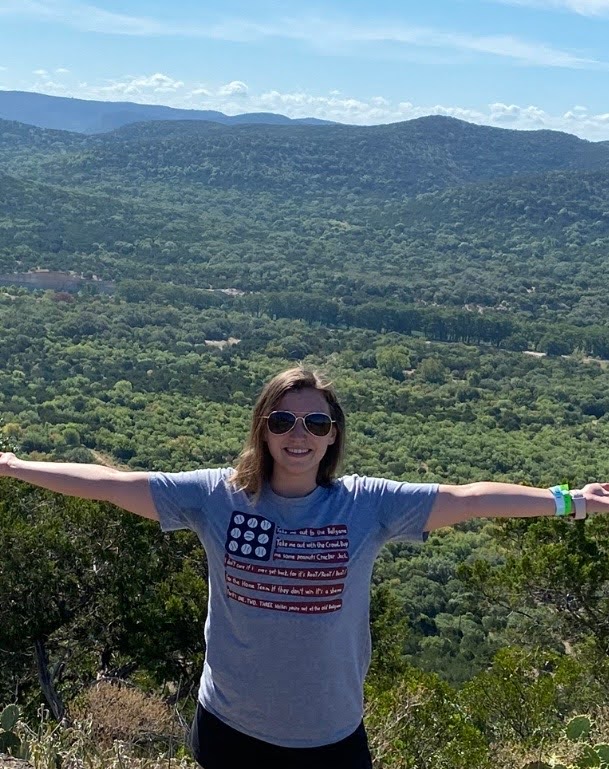 Person enjoying mountain view with open arms.