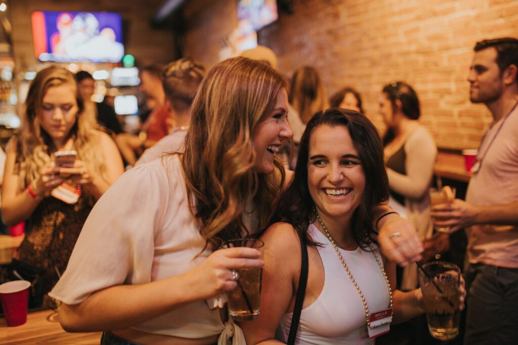 Two women laughing at a lively bar