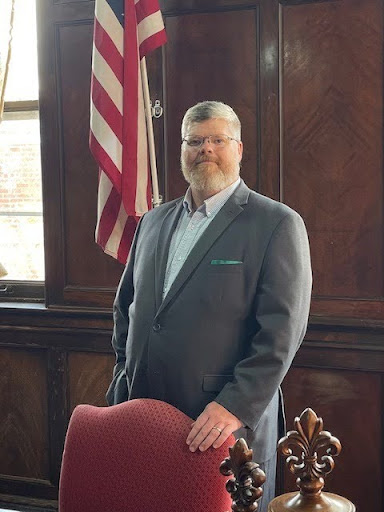 Man in suit standing by American flag.