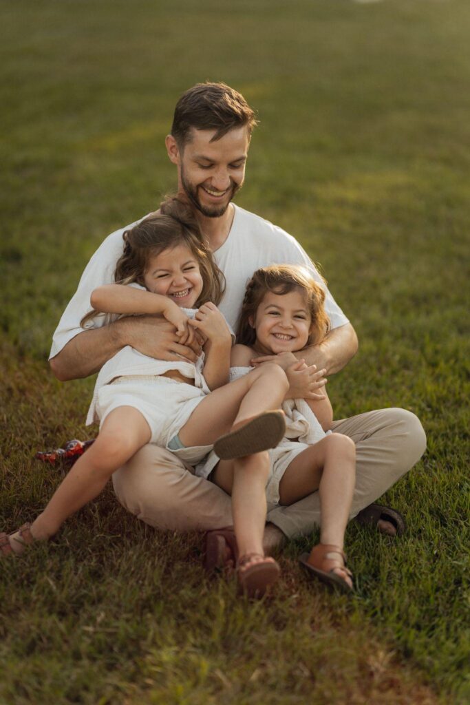 Man with two laughing children outdoors.