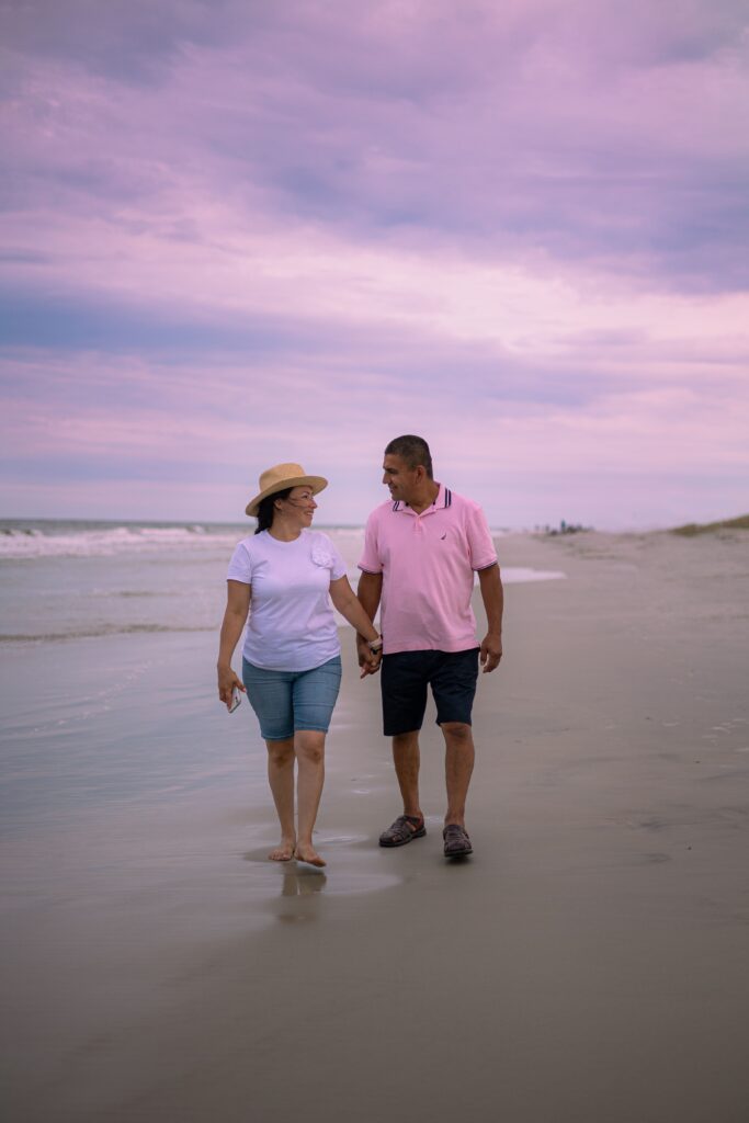 Couple walking on a beach at sunset.