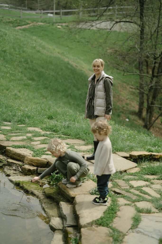 Family by a pond on a grassy hill.